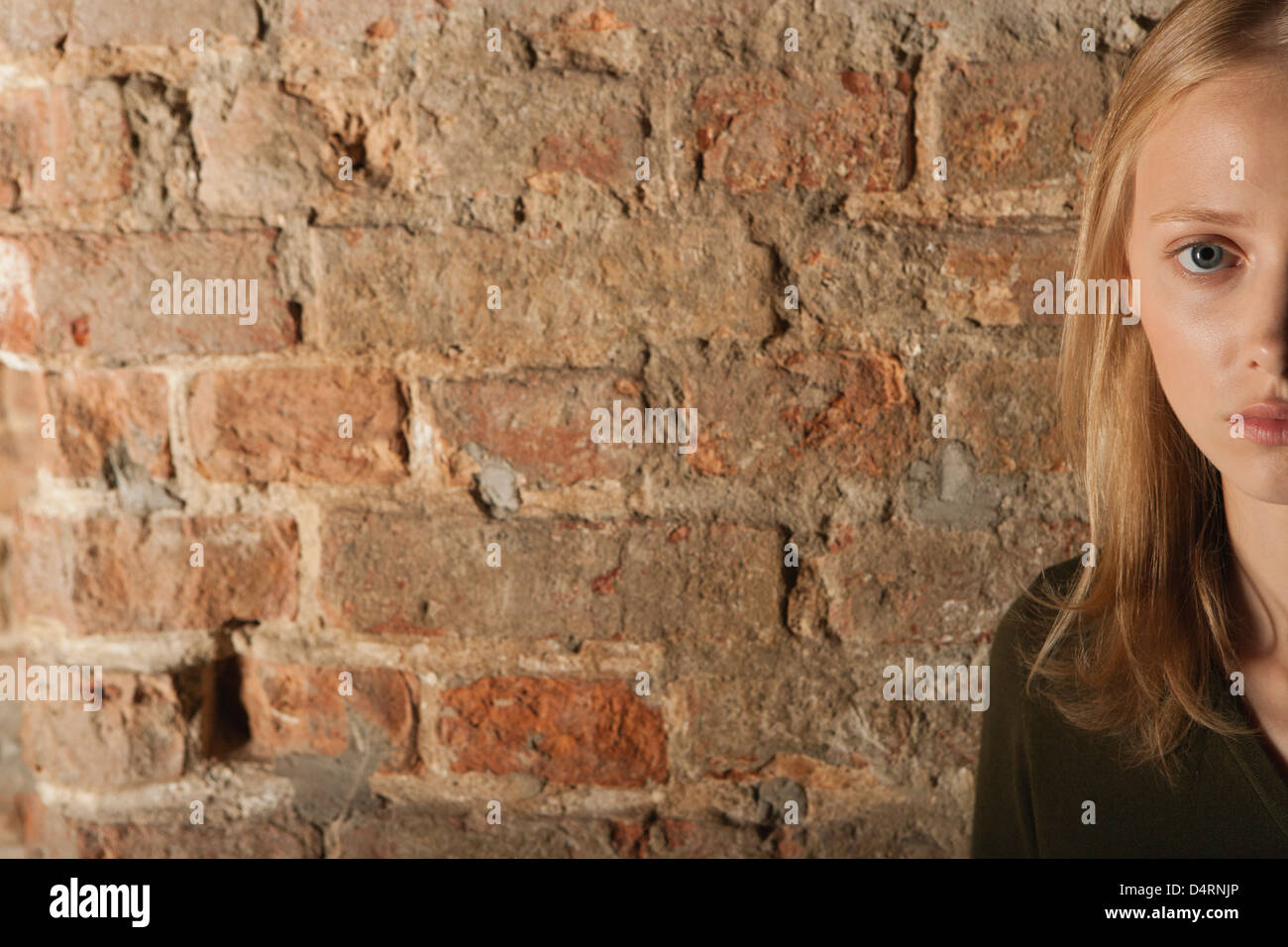 Young woman in front of brick wall, cropped portrait Stock Photo - Alamy