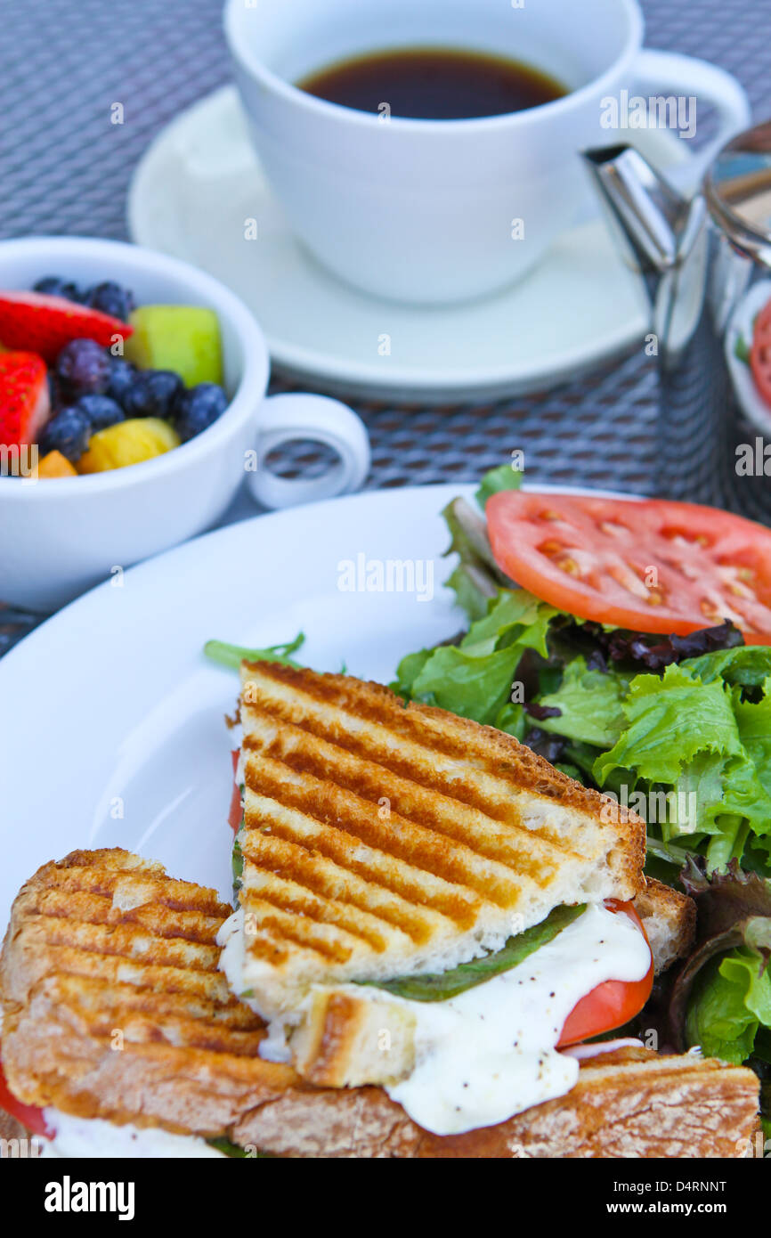 Panini breakfast with complimenting fruits and tea on white plates. Stock Photo