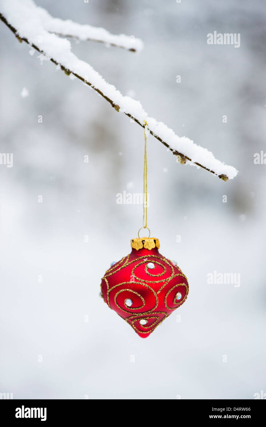 Christmas tree decorations / baubles hanging on a tree branch in the snow Stock Photo
