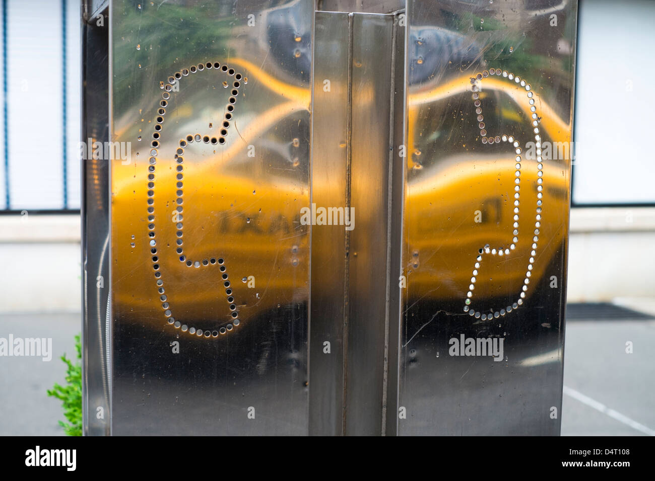 Yellow cab reflected on a street public phone Stock Photo