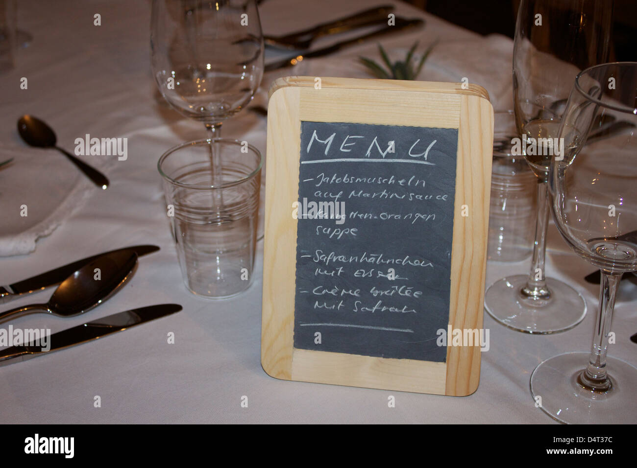 A menu written in German on a blackboard on a white table. Speisekarte auf Deutsch. Stock Photo