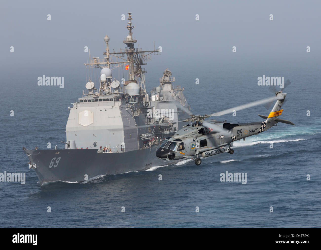 A SH-60J Seahawk flys by USS Vicksburg during a vertical replenishment. Stock Photo