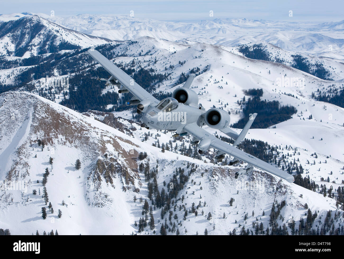 An A-10C Thunderbolt flies over the snowy Idaho countryside. Stock Photo