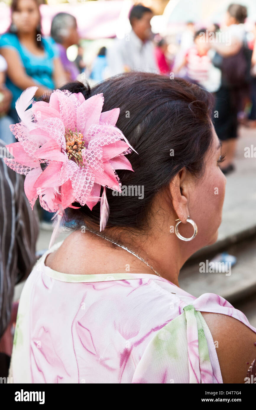 mature Mexican woman outside in crowded park wearing artificial flower in her coiffure & hoop earring Oaxaca de Juarez Mexico Stock Photo