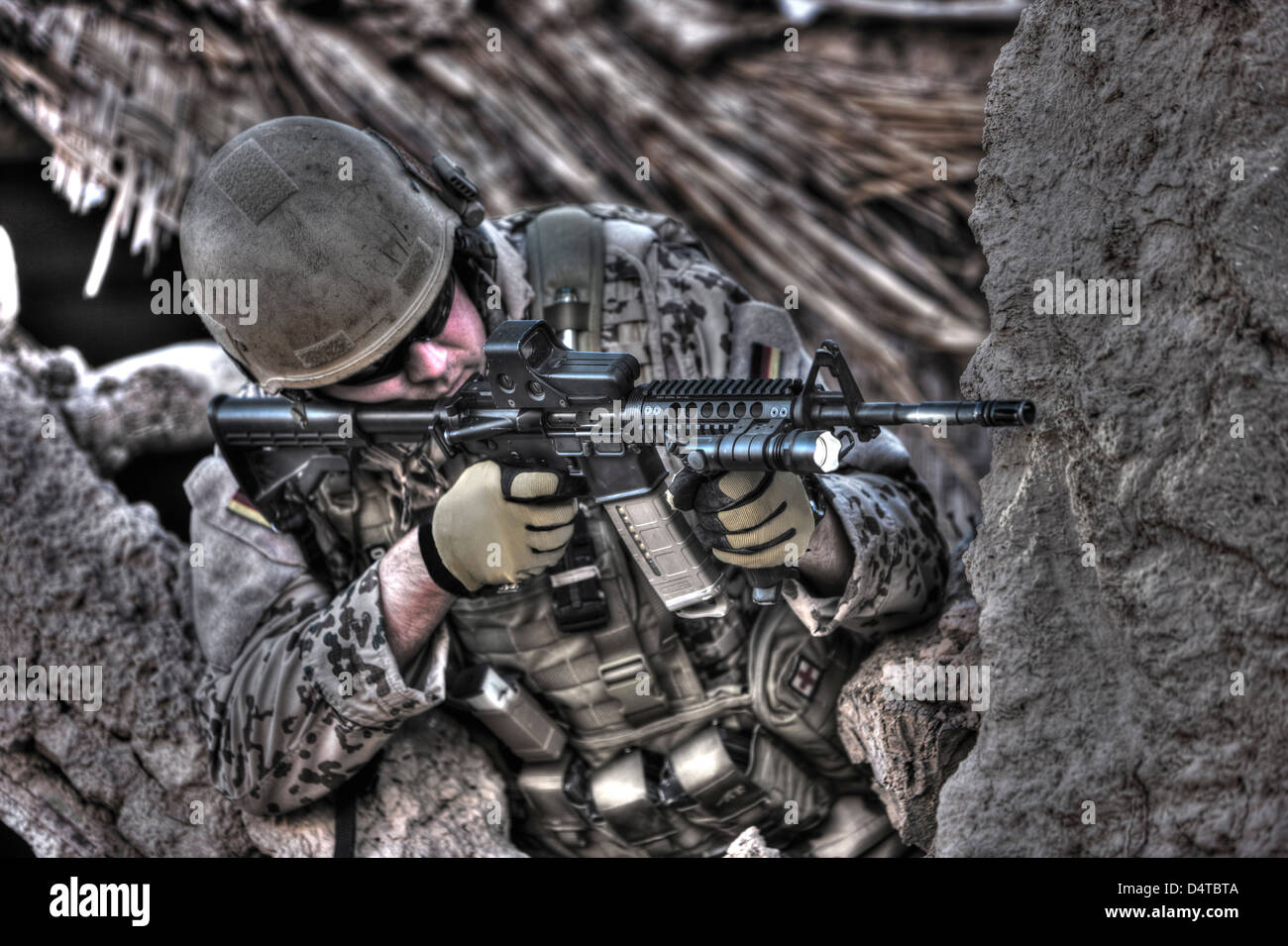 High Dynamic Range image of a German Army soldier armed with a M4 carbine assault rifle in the ruins of a Afghan building. Stock Photo