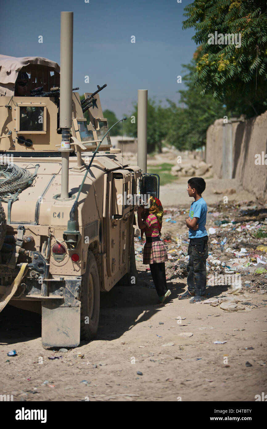 Afghan children ask U.S. soldiers in their humvee for candy on the streets of Kunduz in Northern Afghanistan. Stock Photo