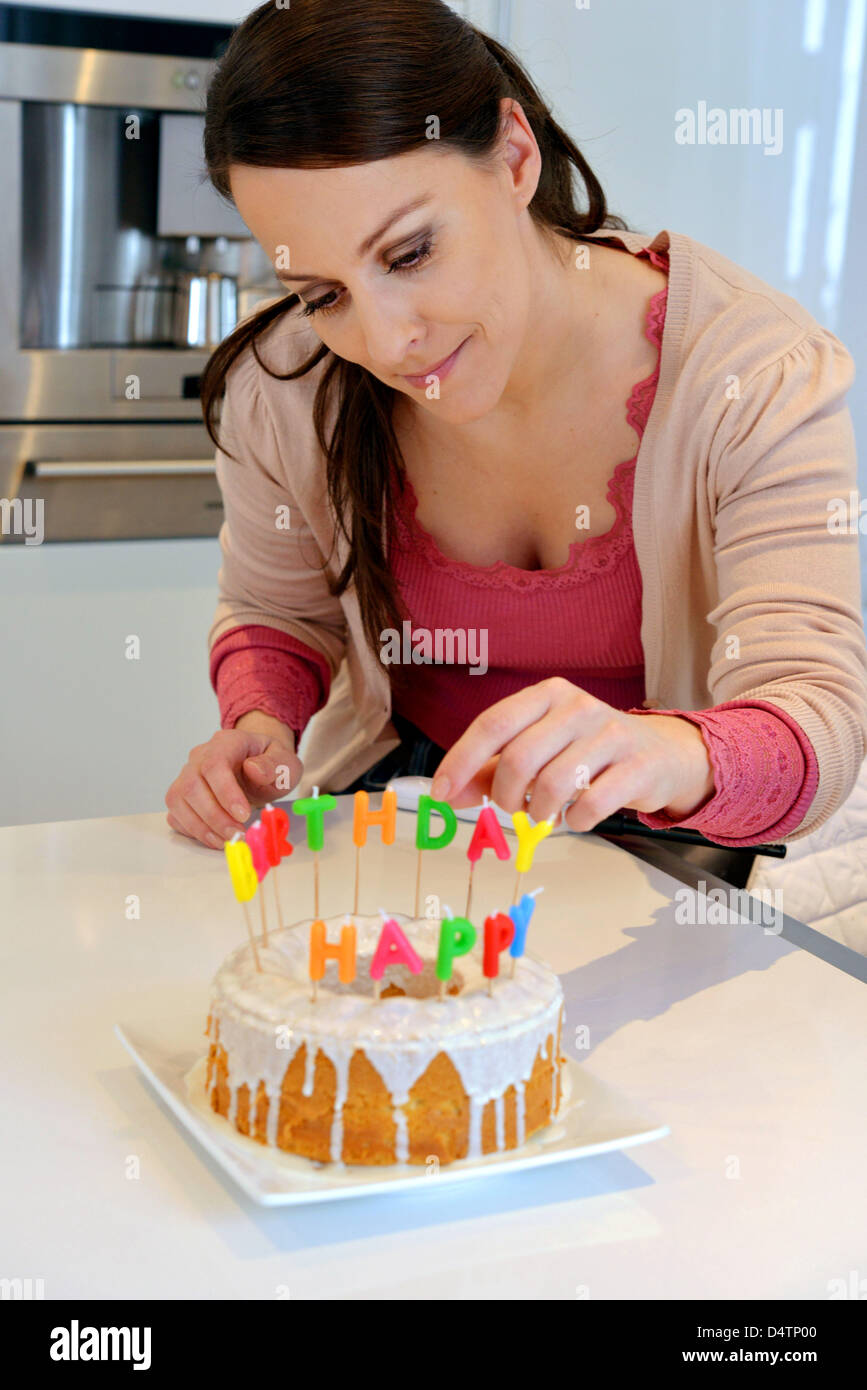 A young woman decorates a birthday cake with candles Stock Photo - Alamy
