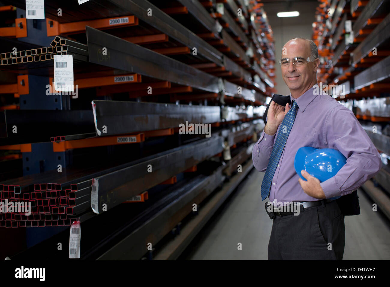 Businessman standing in metal plant Stock Photo