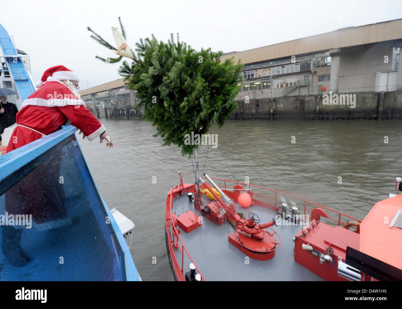 A Santa Claus throws a fir tree onto a ship in the harbour of Hamburg ...