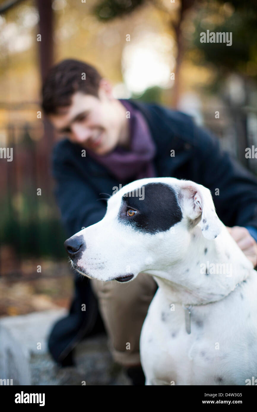 Man petting dog on city street Stock Photo