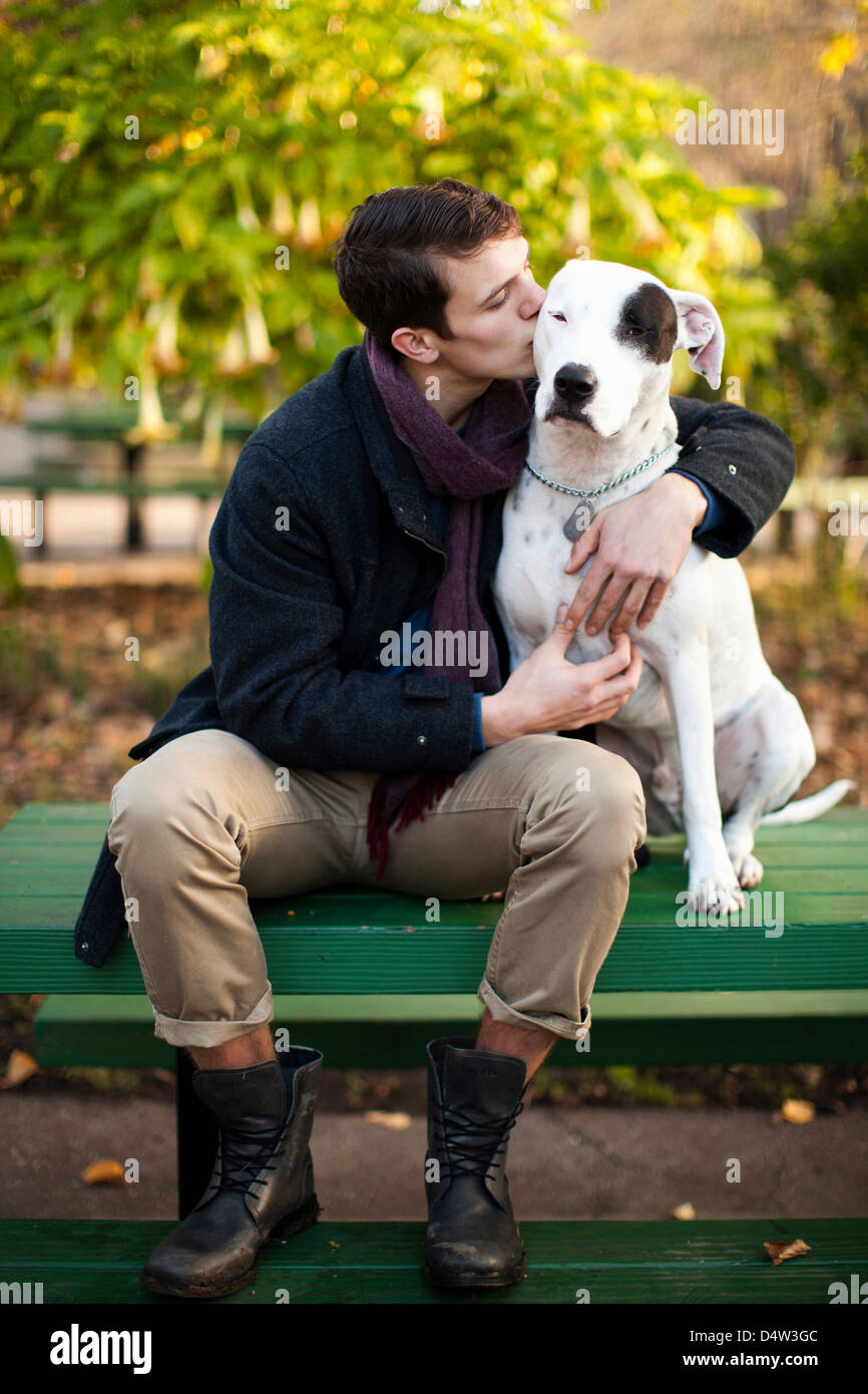 Man petting dog on park bench Stock Photo