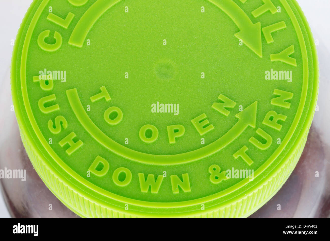 Top of a green twist off cap to a brown pill bottle. Includes arrows and the wording,'Push Down & Turn', and 'To Open'. Stock Photo