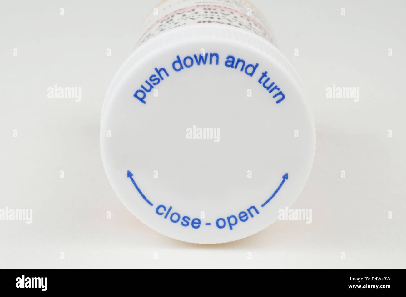 Top of a white pill bottle that reads, 'push down and turn' and 'close-open'. Stock Photo