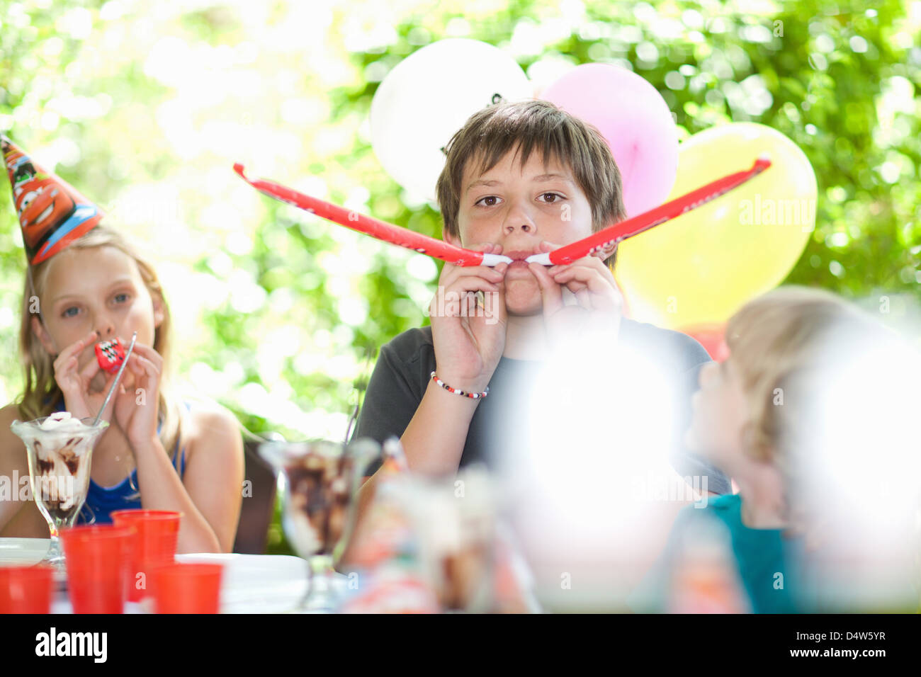 Children blowing noisemakers at party Stock Photo Alamy