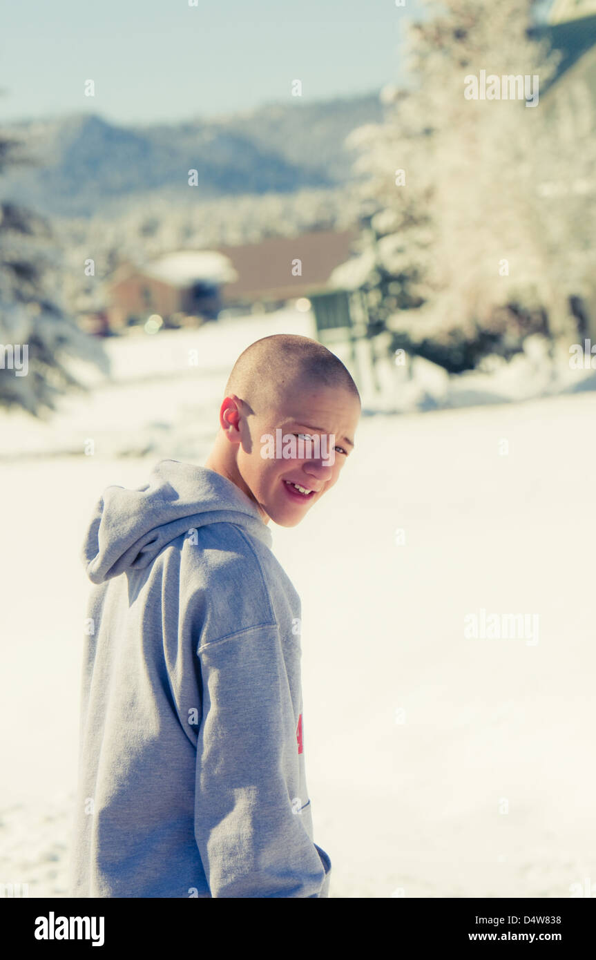 Happy bald boy wearing hood in the snow. Stock Photo