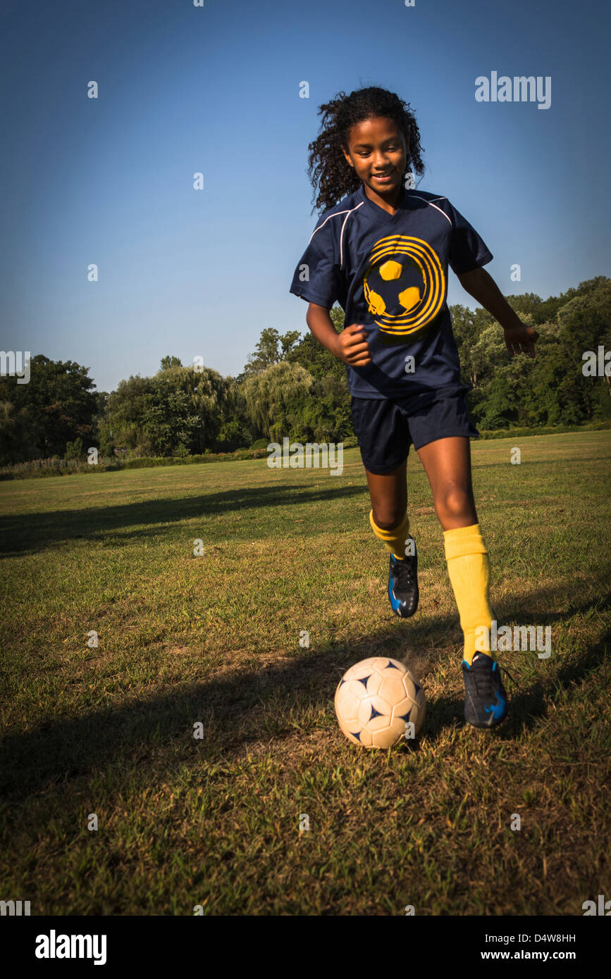 Girl playing soccer in field Stock Photo