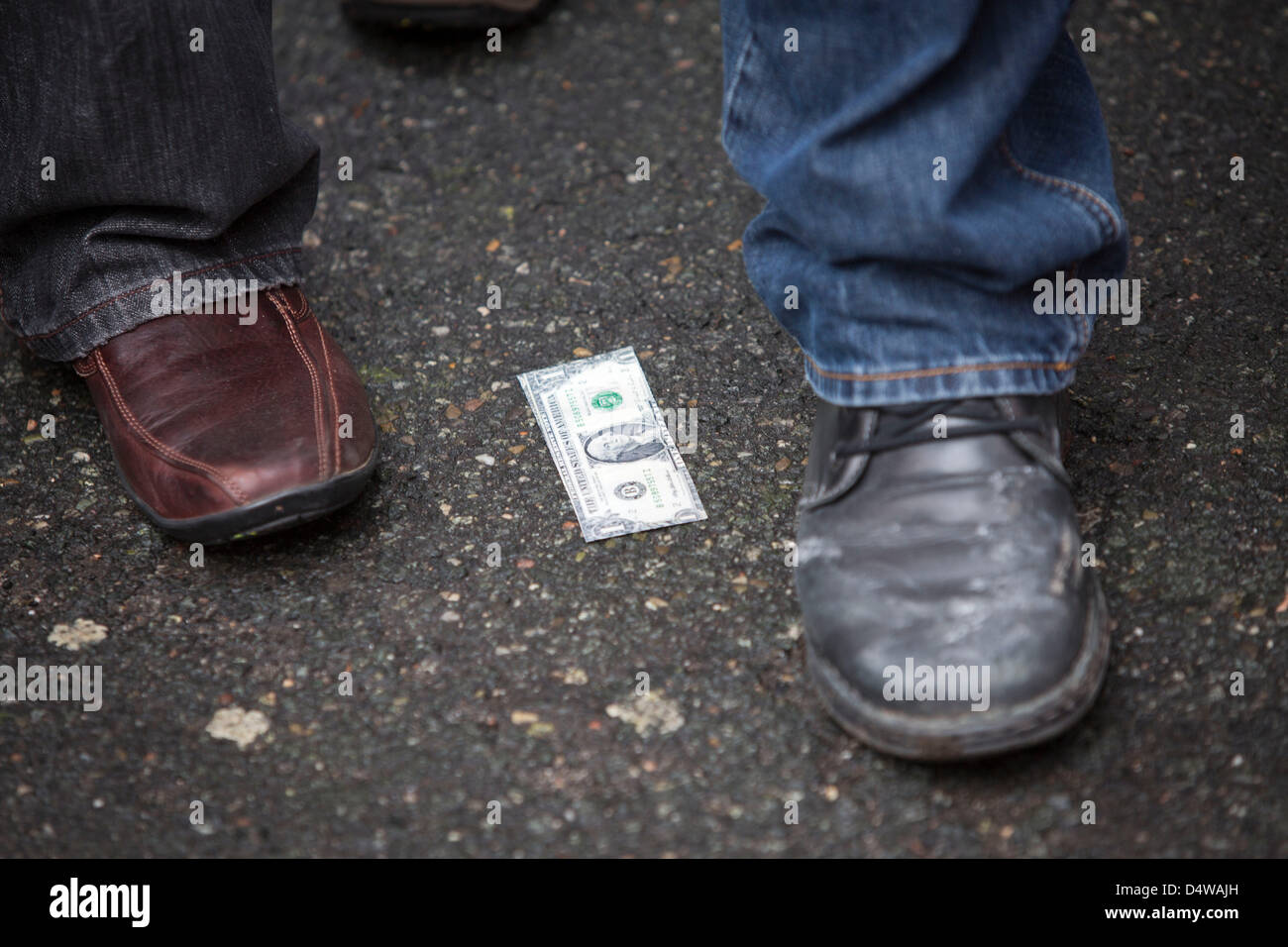 A fake one dollar bill lies on the floor during a rally of about 1000 unionists in front of a hotel in which the regional pay negotiations for employees of the metal and electrical industries takes place in Darmstadt, Germany, 19 March 2013. The union IG Metall demands an increase in salary of 5.5 percent. Photo: Frank Rumpenhorst Stock Photo