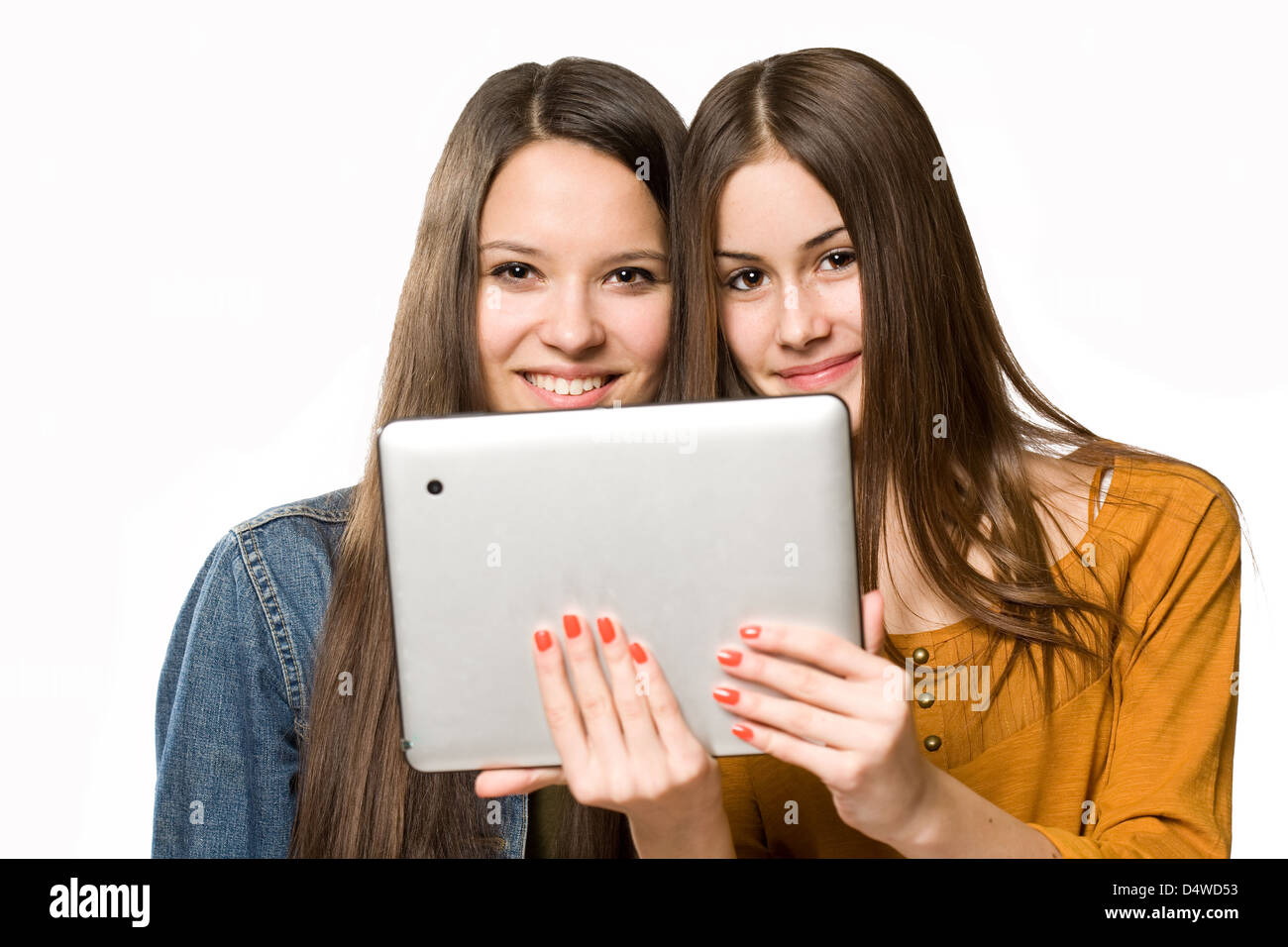 Portrait of a cute teen girls sharing a tablet computer. Stock Photo