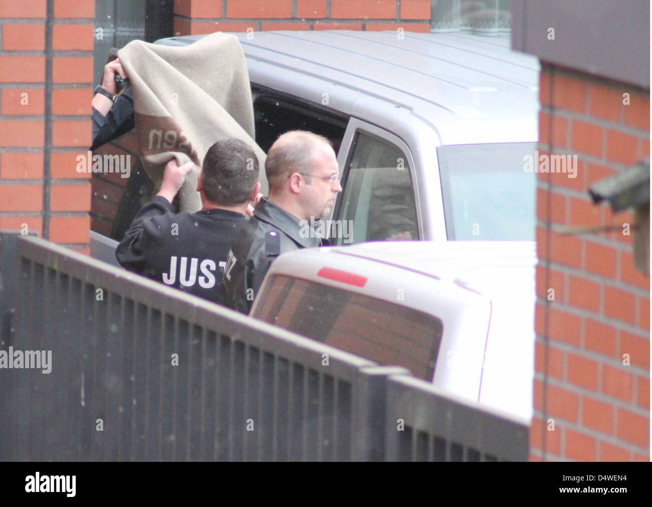 The suspect of the Bodenfelde murder case gets out of a police car and is covered with a blanket in Northeim, Germany, 26 November 2010. Jaqn O. has confessed to have committed the murder on two adolescents in Bodenfeld. The suspect confessed in front of the investigative court, according to information released by the Public Prosecution Service Goettingen. The unemployed man confe Stock Photo