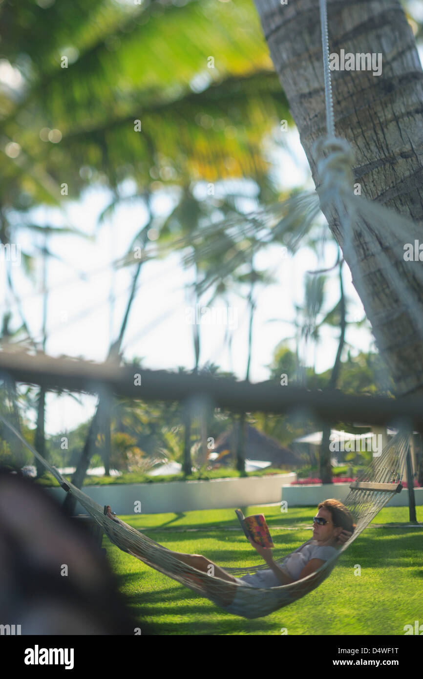 Man in hammock under palm trees Stock Photo