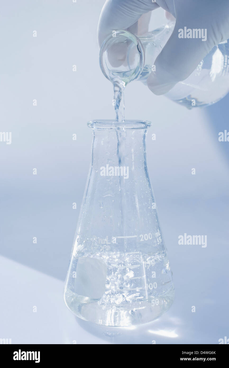 Scientist pouring liquid into beaker Stock Photo