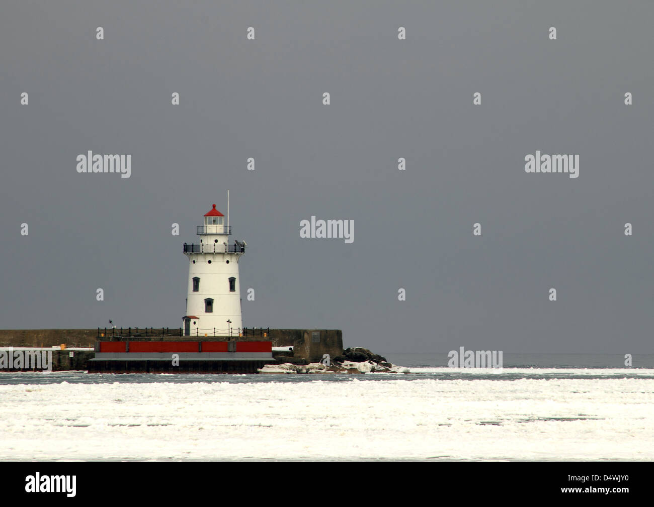 Standing Guard. Harbor Beach, Michigan lighthouse standing guard over a frozen Lake Huron. Stock Photo