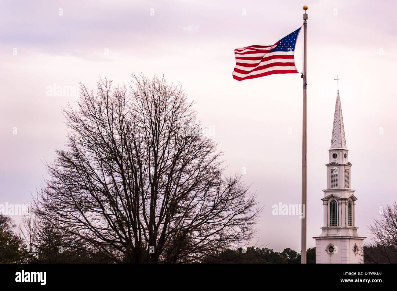 Community values of faith and patriotism are seen in the symbols of a waving flag and cross-topped steeple. Stock Photo