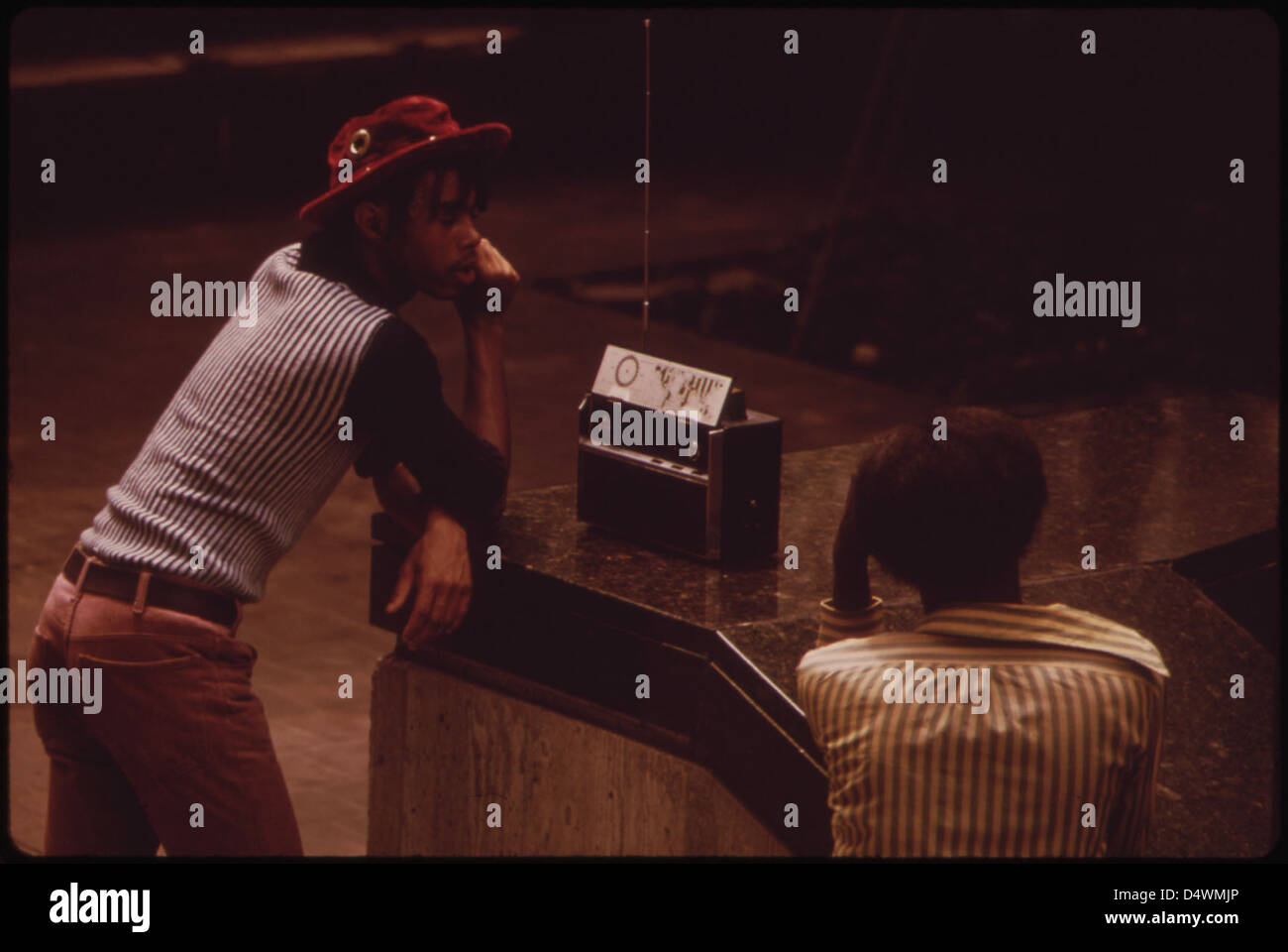 A 1973 photograph from the DOCUMERICA project by the Environmental Protection Agency, depicting a person listening to a transistor radio in Fountain Square, capturing a moment of daily life in the 1970s. Stock Photo