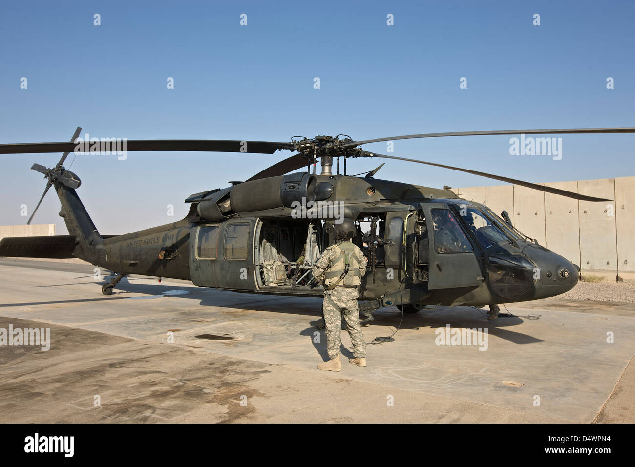 A U.S. Army crew chief stands by while pilots go through their pre-start checks on a UH-60 Black Hawk, Tikrit, Iraq. Stock Photo