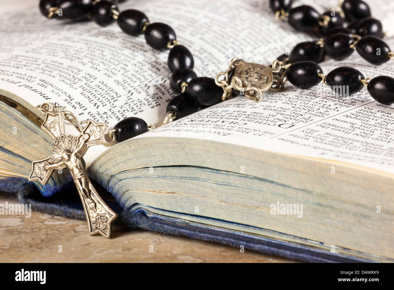 Rosary beads and cross lying on an open page of the bible Stock Photo ...