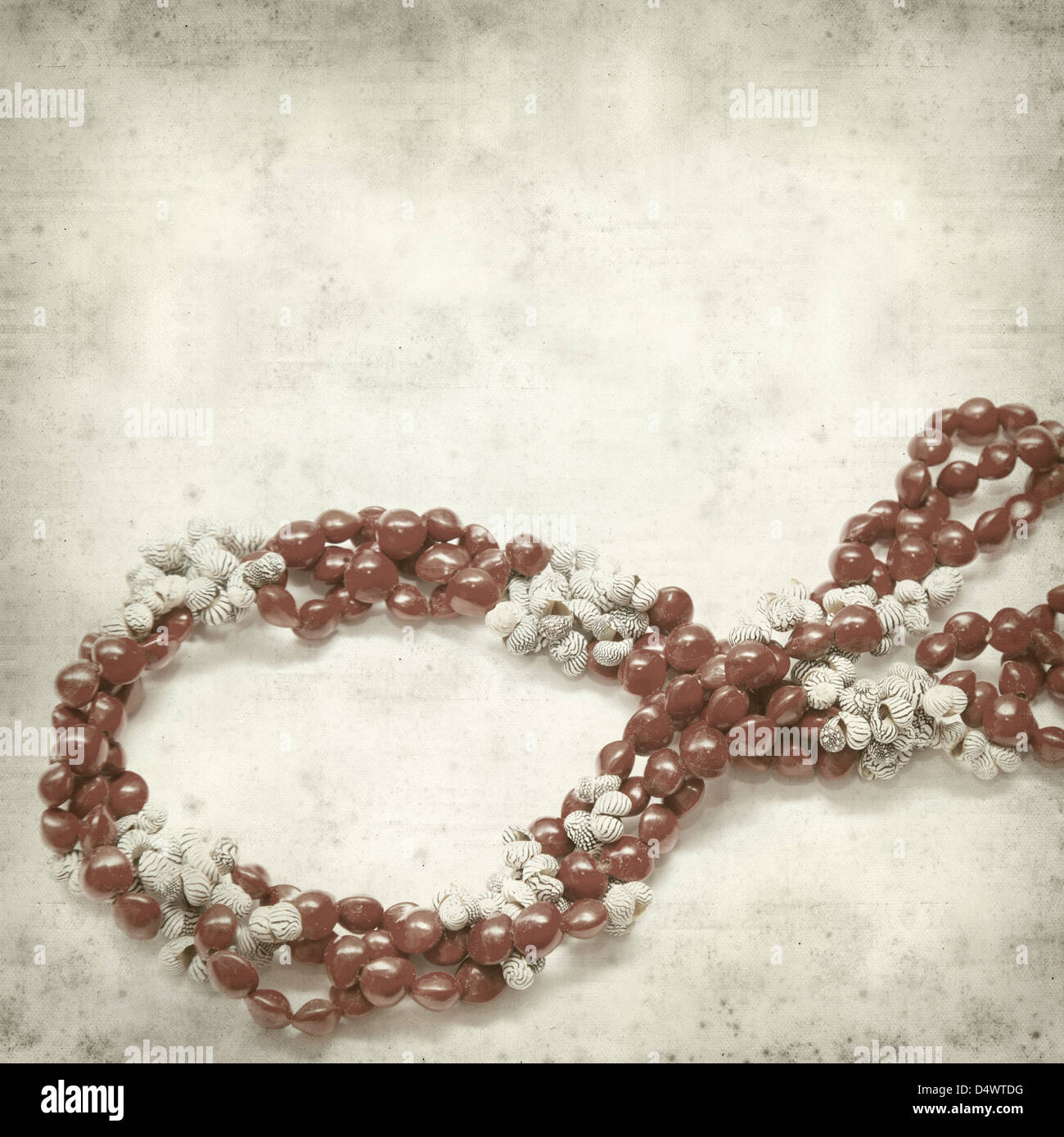 textured old paper background with necklace of seeds and shells Stock Photo