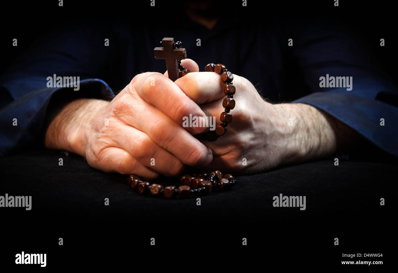 Hands holding rosary beads and cross while praying. Stock Photo
