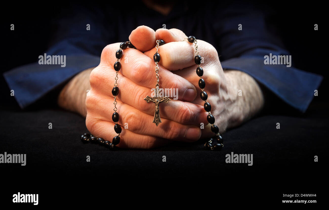 Hands holding rosary beads and cross while praying. Stock Photo