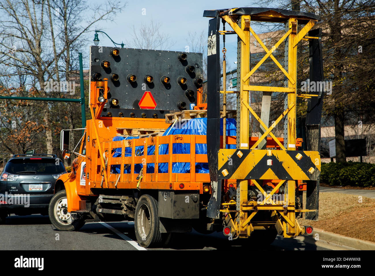 A truck loaded with road construction equipment pulling into road traffic Stock Photo