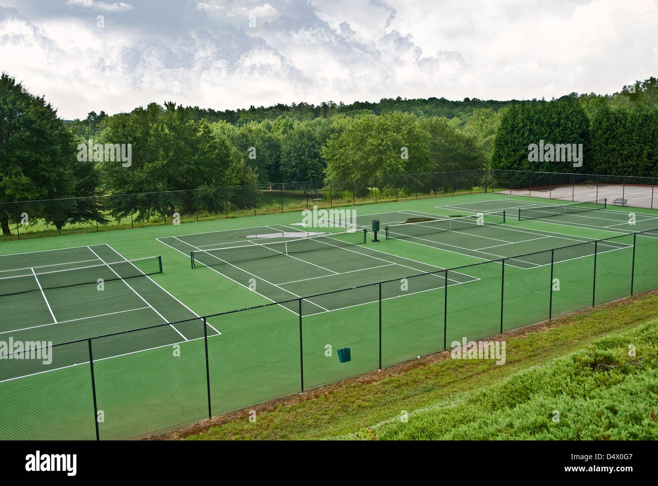 Tennis courts that have been abandoned because of rainy weather, there are puddles of water on some. Stock Photo