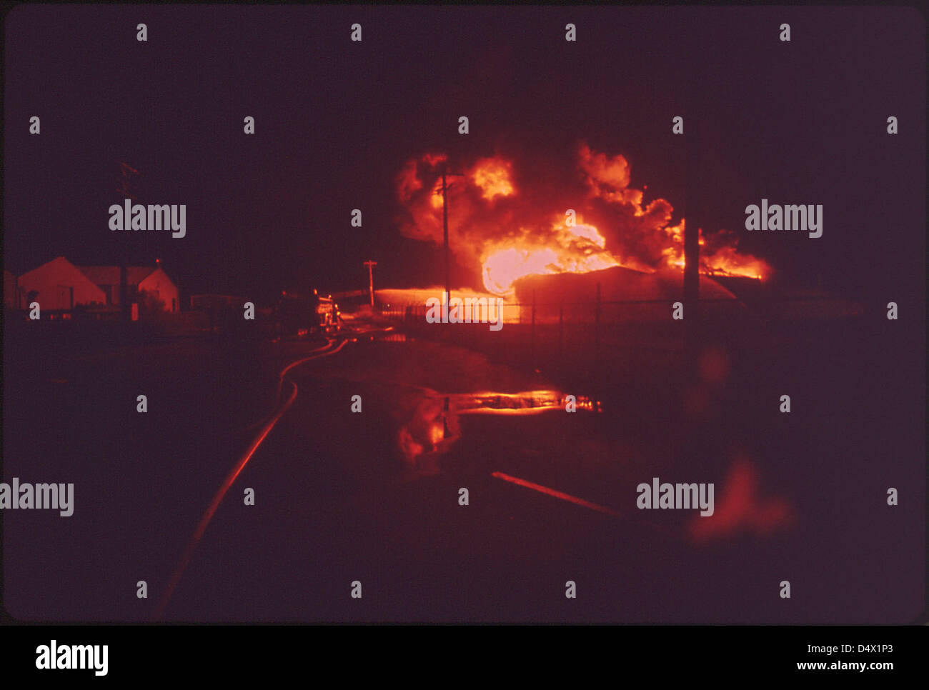 A Texaco crude oil tank burns brightly at night after being struck by lightning in May 1972. The image captures the intensity of the fire and the dramatic contrast of light against the dark sky. This event was documented by the Environmental Protection Agency and archived by the U.S. National Archives. Stock Photo