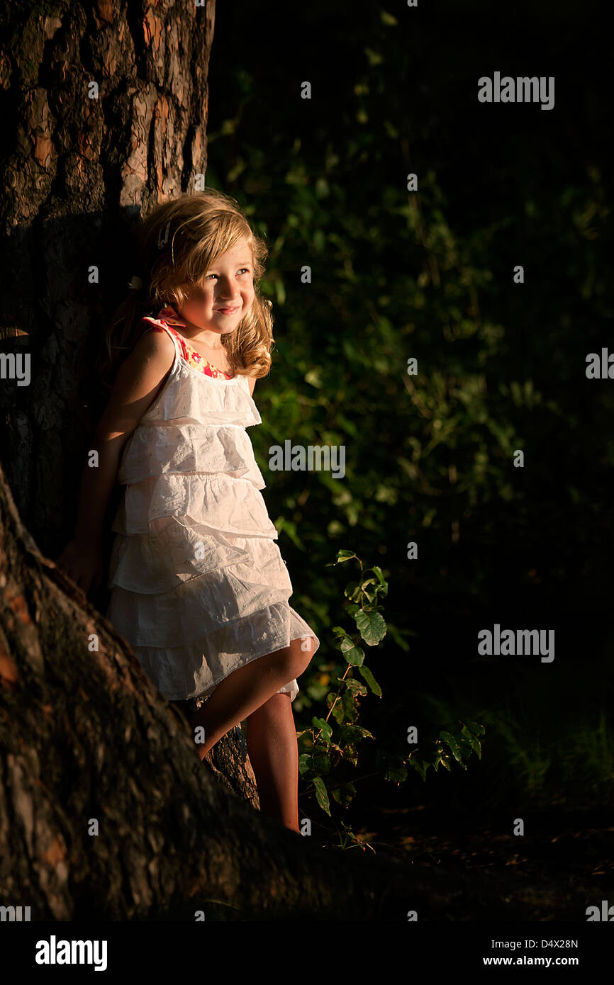 little smiling girl posing next to the tree Stock Photo - Alamy