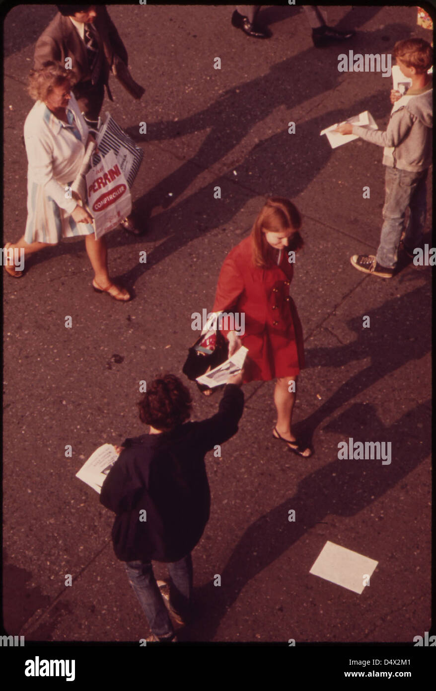 Without Breaking Stride, Homeward Bound Commuter at the Staten Island Ferry Terminal Reaches for Leaflet from Street Distributor 05/1973 Stock Photo