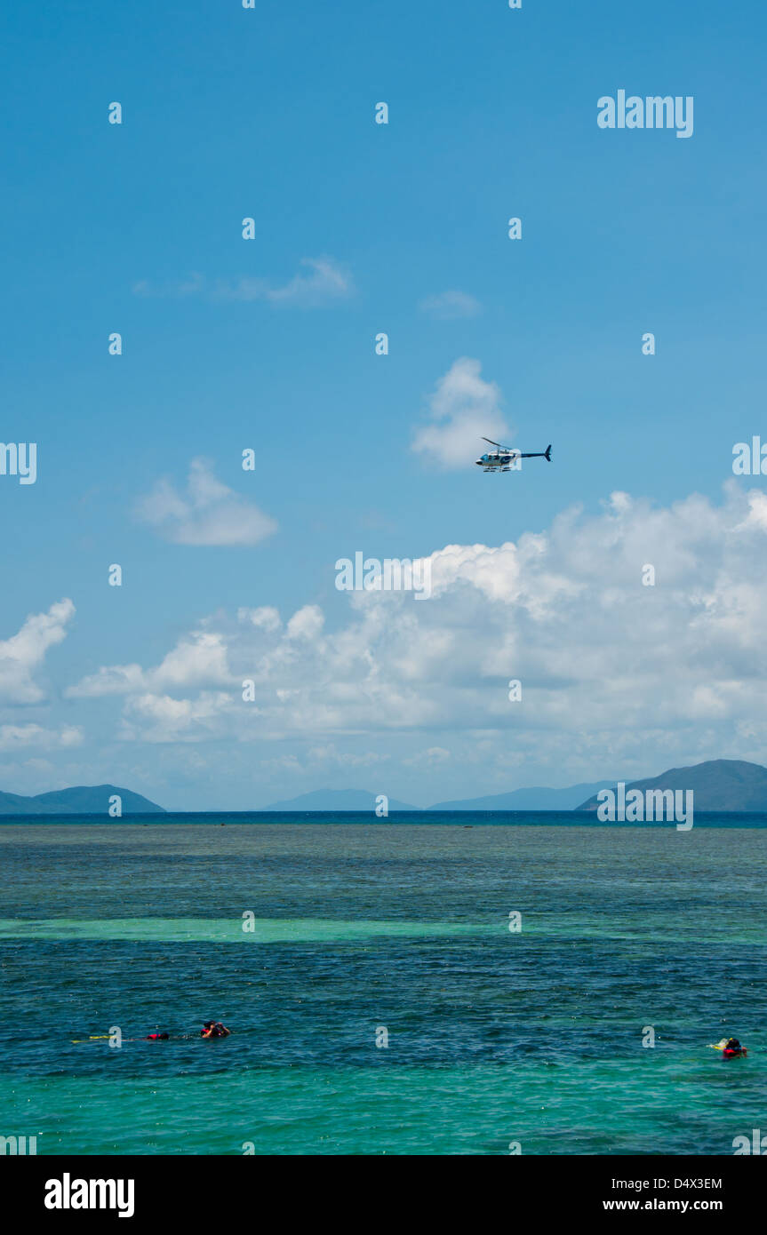 Great Barrier Reef. A helicopter takes sightseers to Green Island while snorkelers enjoy a sunny summer day below. Stock Photo