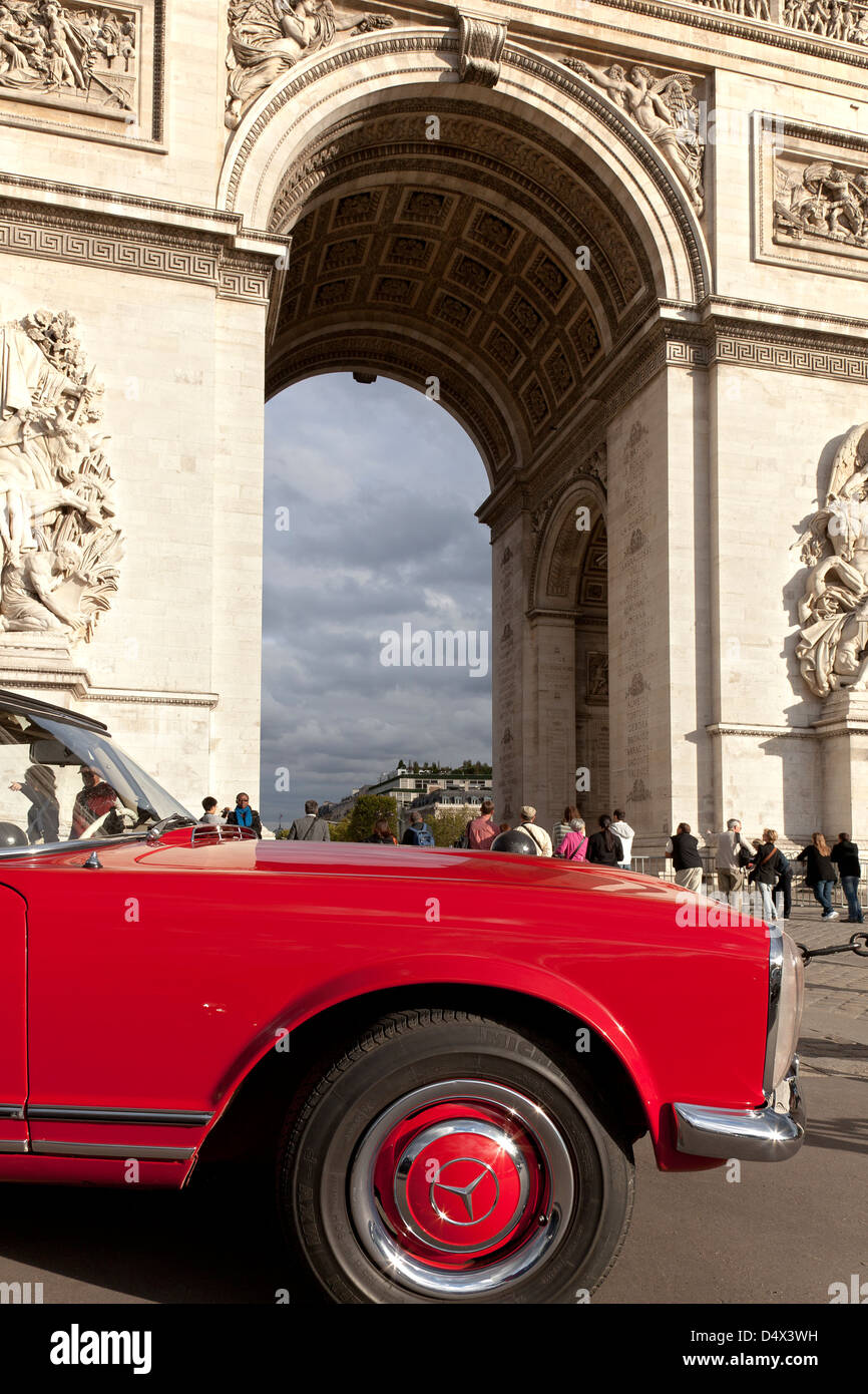 red Mercedes veteran car in front of the Arc de Triumph in Paris; L’Arc de Triomphe de l’Étoile in Paris Stock Photo