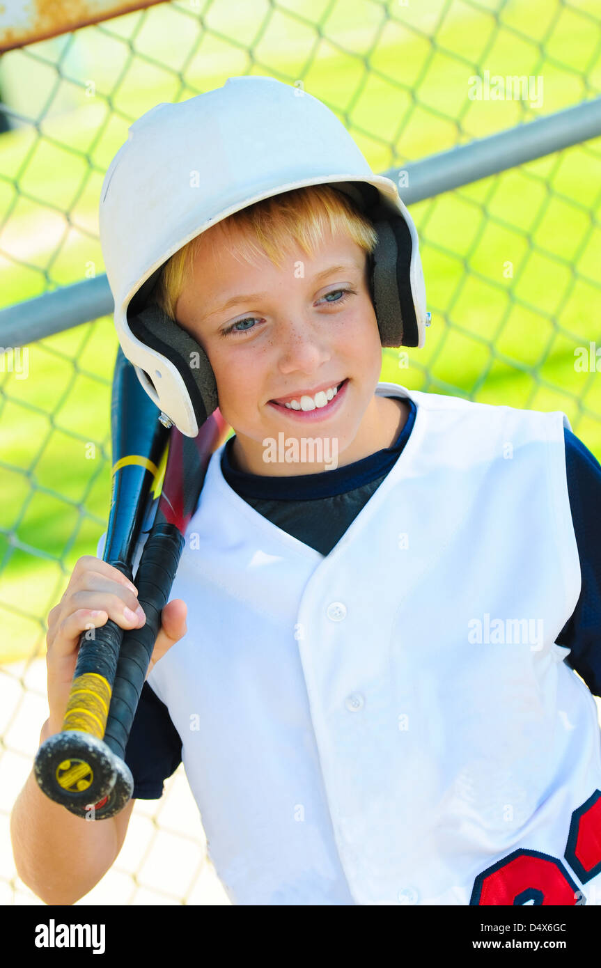 Cute baseball player smiling in the dugout about to go bat Stock Photo