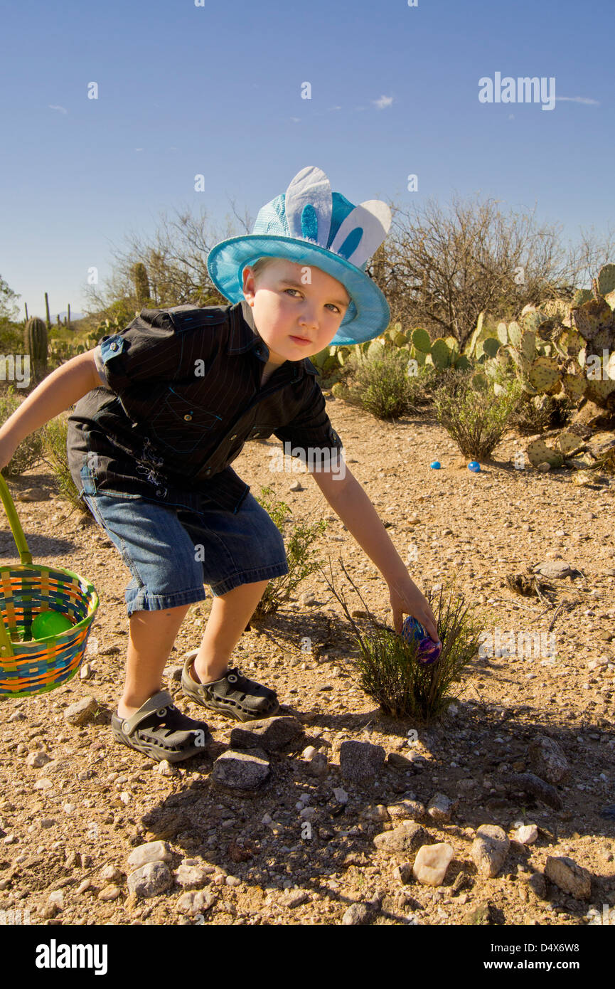 An autistic five year old boy cautiously hunts for Easter eggs in the desert. Stock Photo