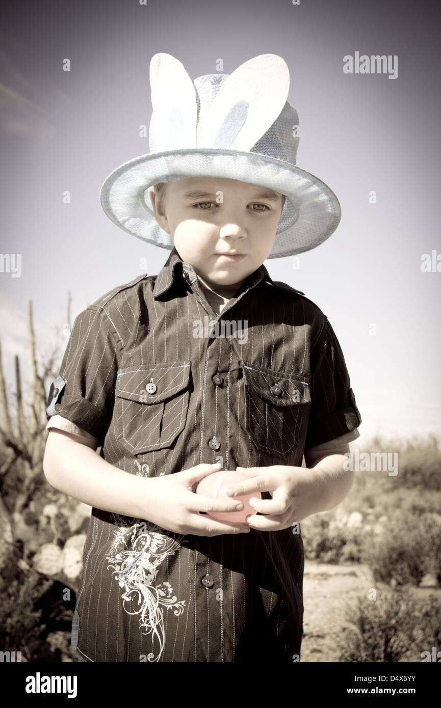 A five year old boy with autism takes a moment to himself while hunting for plastic Easter eggs in the desert. Stock Photo