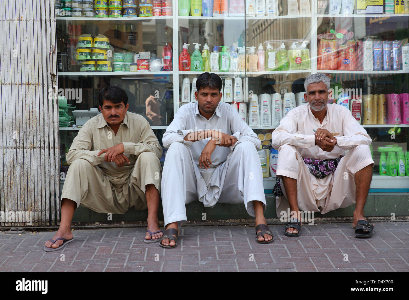 Three men sitting on a street in Dubai, United Arab Emirates Stock Photo