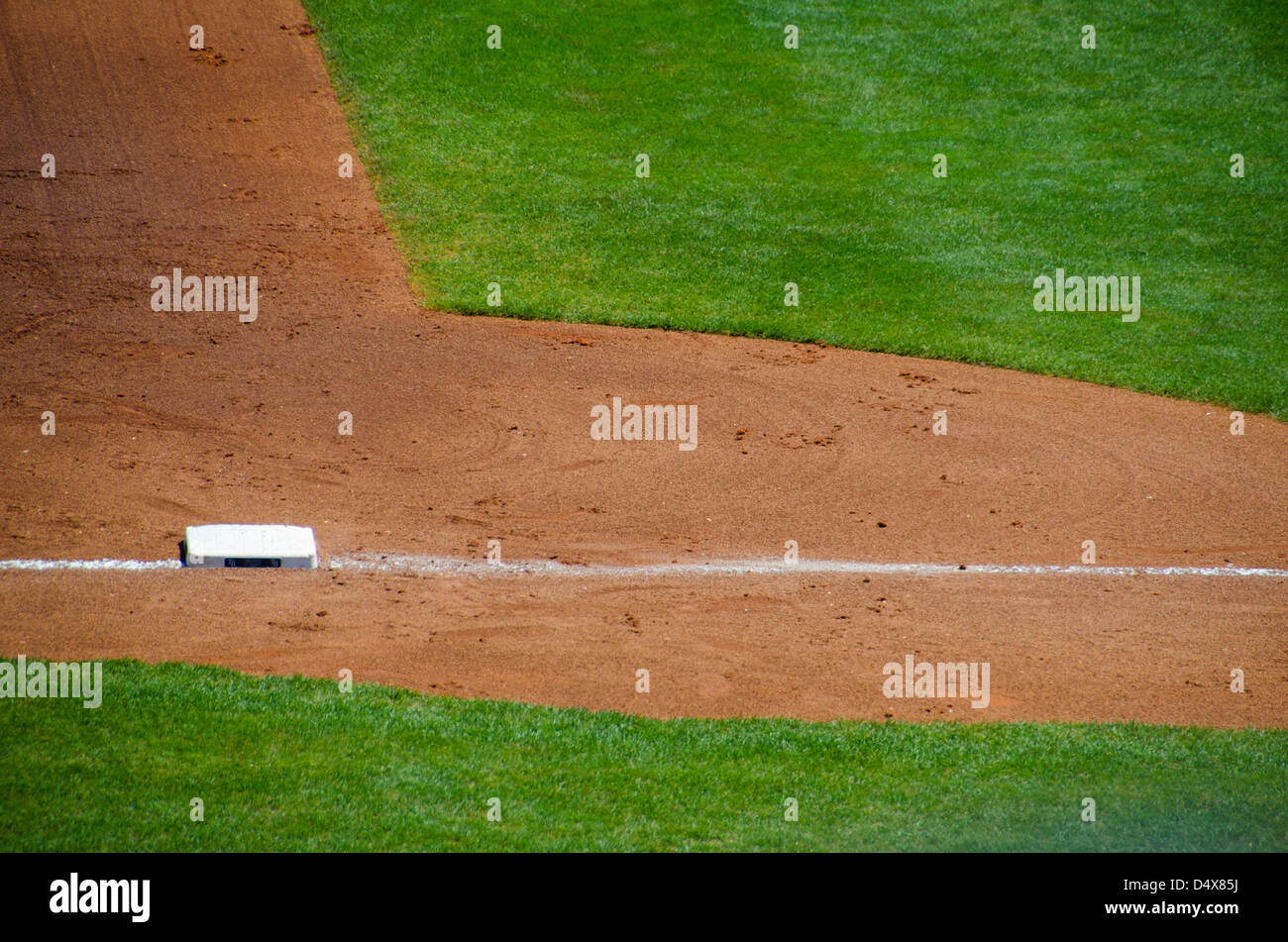 Abstract background texture of the brown dirt and green grass of a professional baseball field with third base line and base Stock Photo