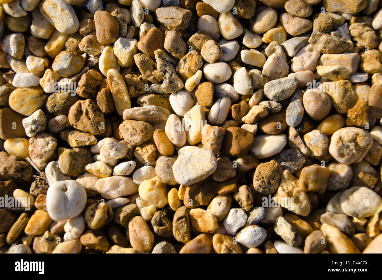 Sunny natural background texture featuring the bright orange, white and brown rocks and pebbles of a landscaped Florida home Stock Photo