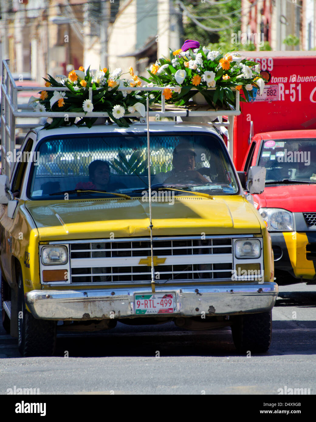 A delivery truck carries flower arrangements on the roof and a family in the cab, Oaxaca, Mexico. Stock Photo