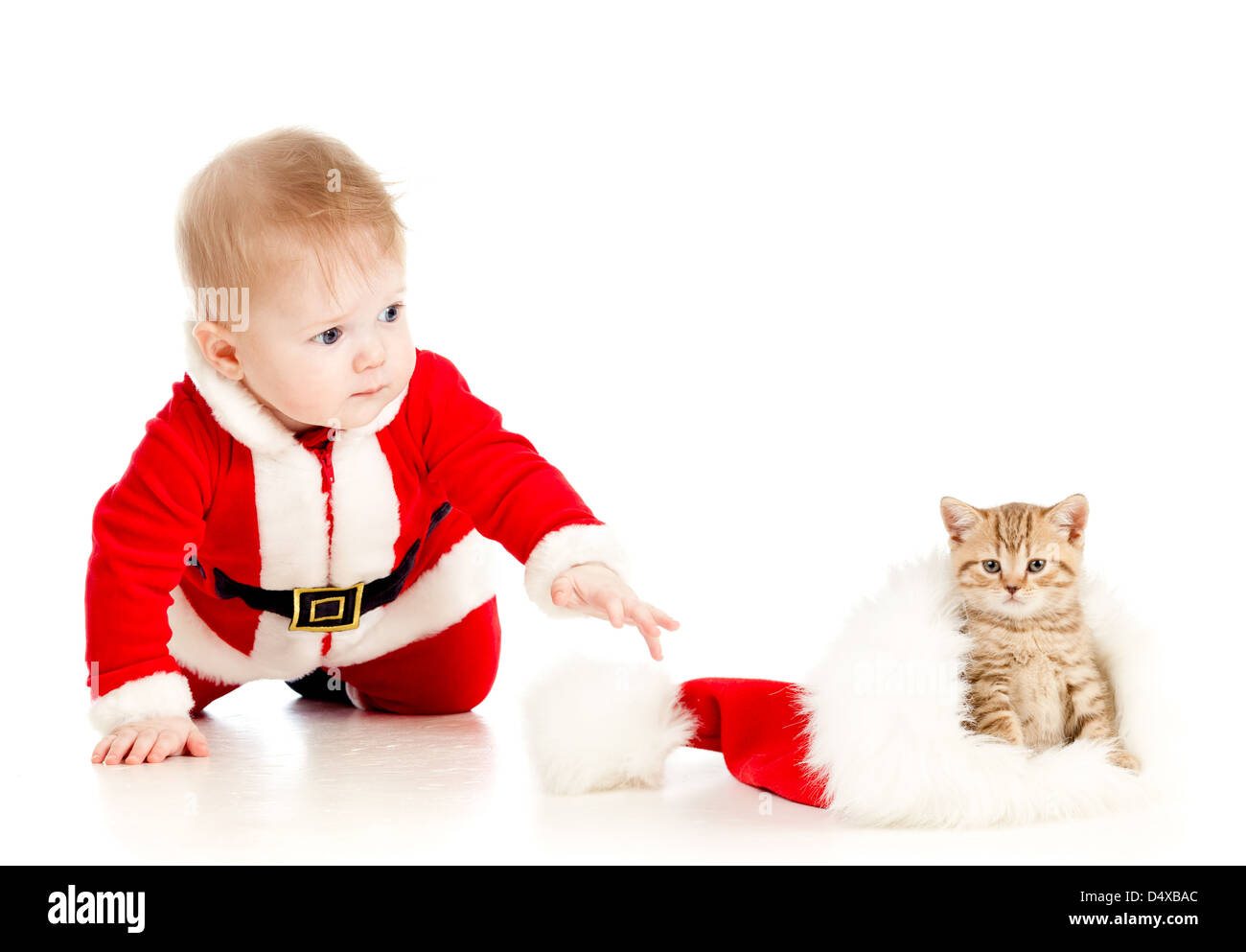 christmas baby reaching out hand for cat in a santa claus hat Stock Photo