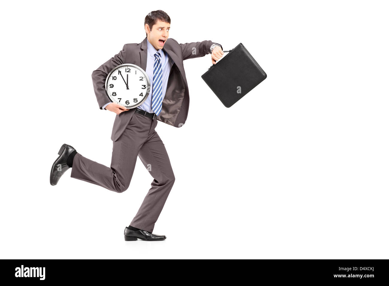 Full length portrait of a young businessman running late with a clock and a briefcase isolated on white background Stock Photo