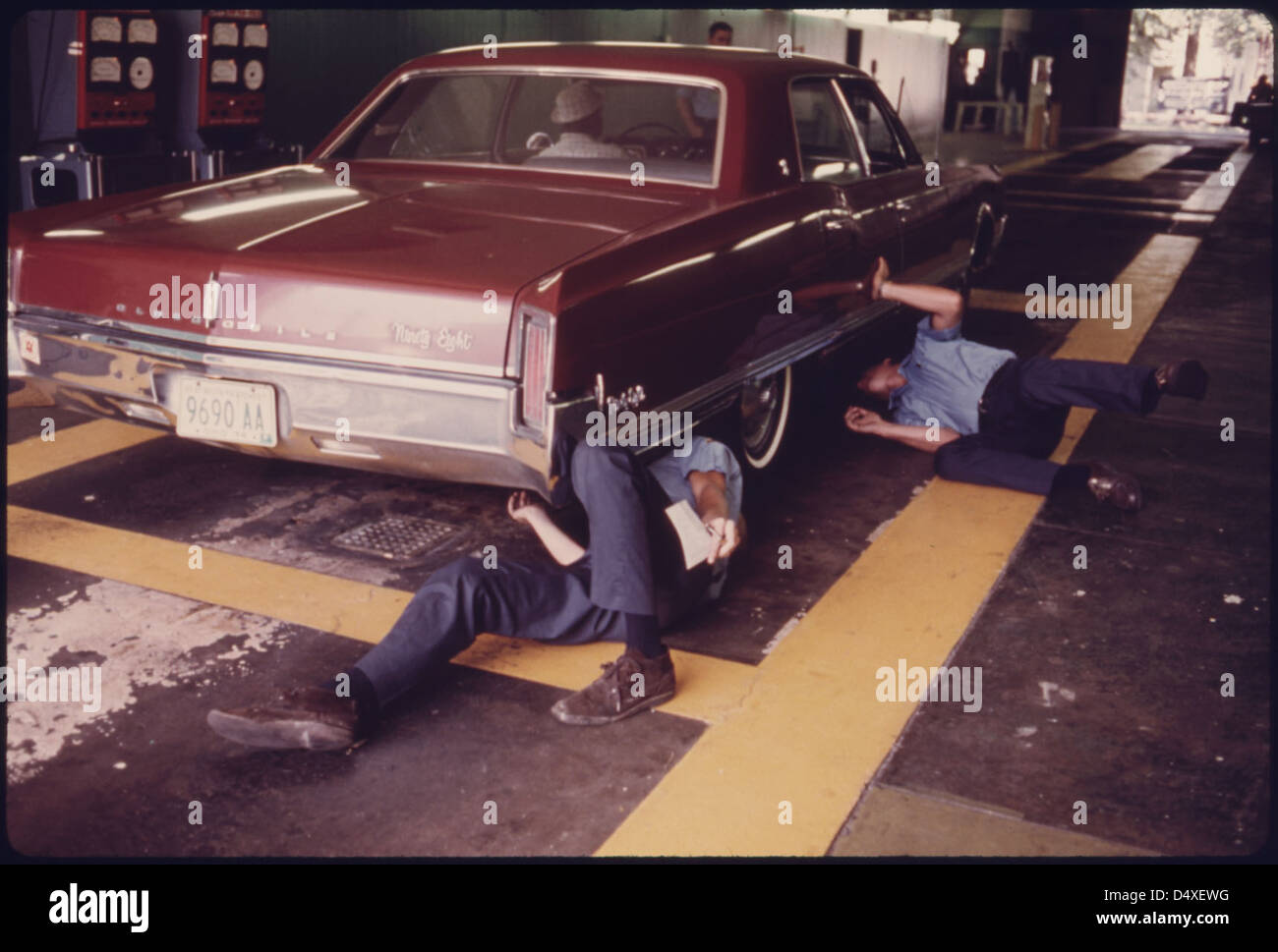 Public Works Department Employees Inspect the Exhaust System for Visible Leaks at an Auto Emission Inspection Station in Norwood, Ohio...08/1975 Stock Photo